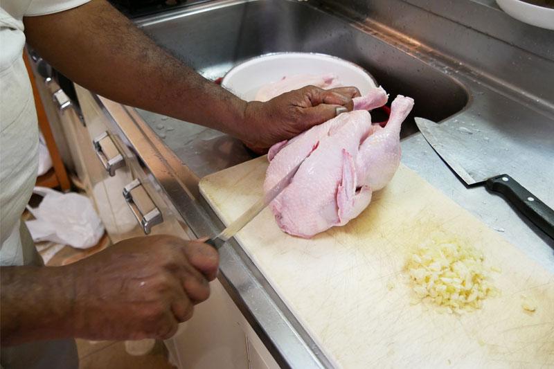 玉ねぎを炒め続ける間に、丸鶏をぶつ切りにしていきます