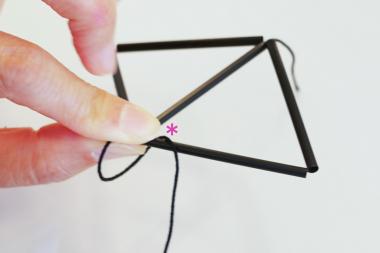 今度は新しくできた三角形の角を指で押さえながら、*位置の下から針を通して糸を掛け、角で糸を引き締める